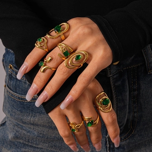 Set of 8 gold stainless steel spiral rings with emerald green zircon stones on hand