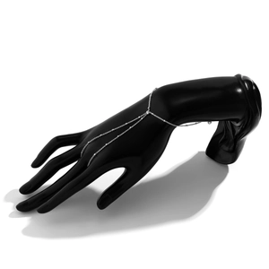 Detailed view of a silver-tone rhinestone finger bracelet chain on a black hand model