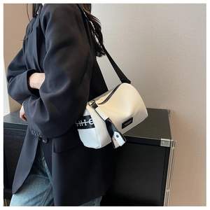 Close-up of a white cylinder crossbody bag with black straps and fashion logo detail