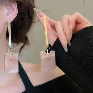Detail of pink marble pattern resin drop earrings with gold metal bar on model