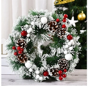 Detalle en primer plano de una corona de Navidad nevada con piñas y bayas rojas