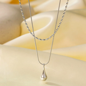 Double-layer silver stainless steel necklace with water drop pendant on cream satin
