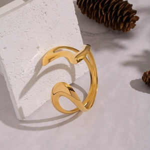 Bracelet jonc ouvert ondulé minimaliste doré 18K posé sur une base en pierre texturée