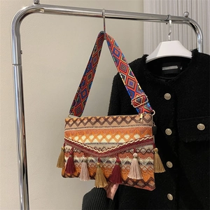 Detail of bohemian woven crossbody bag with geometric patterns and colorful tassels