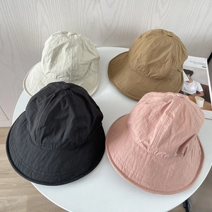 Top view of four nylon sun hats in cream, khaki, black and pink on a stylish table