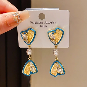 Macro detail of S925 silver earrings with blue crystal heart and teardrop pearl