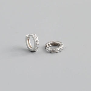 Macro detail of silver S925 huggie hoop earrings with sparkling cubic zirconia inlay