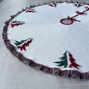 Detail of knitted Christmas tree skirt with red and green patterns and colorful tassels