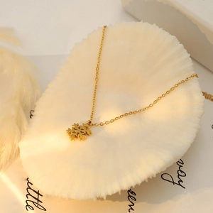 Close-up of elegant 18k gold snowflake pendant on a fine chain over artistic cards