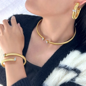 Detail of gold tubular choker necklace and earrings set with crystal rhinestones