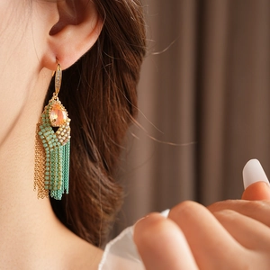 Close-up of bohemian tassel earrings with orange gemstones and turquoise beads