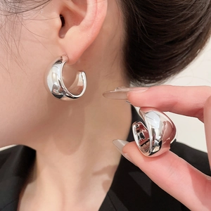 Detail view of silver C-shaped minimalist earrings with polished metallic finish
