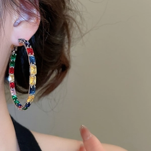 Close-up of silver hoop earrings with vibrant colorful rectangular zircons worn by model