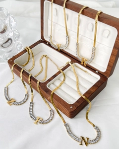 Detail of 18K gold letter pendants with baguette-cut zircons on flat snake chains