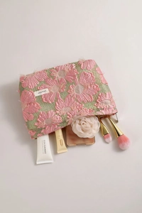 Detailed interior of pink floral jacquard makeup bag with brushes and cosmetics