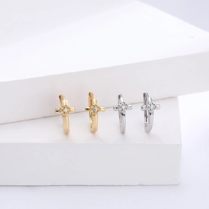 Macro detail of gold and silver S925 sterling silver cross hoop earrings on white stone
