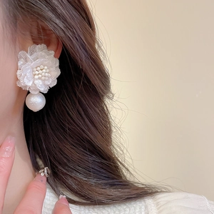 Detailed close-up of white lace flower earrings with pearls and delicate bead centers