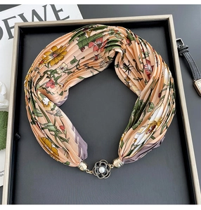 Detail of pleated floral scarf necklace with golden flower clasp and white pearl accent