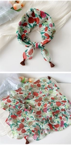 Close-up of floral linen scarf featuring red flower patterns and dark brown corner tassels
