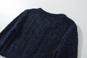 Dettaglio macro della trama in maglia tweed blu navy sul colletto del cardigan