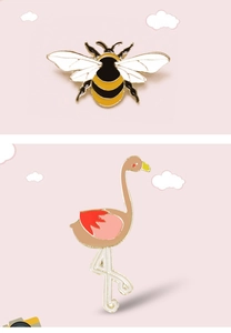 Detail of bee and flamingo enamel pins on a soft pink background with cloud decor