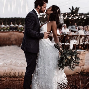 Elegante abito da sposa in pizzo bianco con spalline sottili e spacco per matrimoni all'aperto