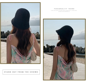 Détail d'un chapeau cloche en tricot noir avec une robe à fleurs sur une plage ensoleillée