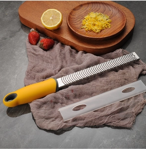 Macro detail of stainless steel zester with yellow handle and clear protective cover