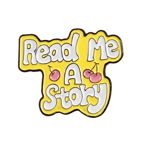 Yellow enamel brooch featuring Read Me A Story text and pink cherry illustrations