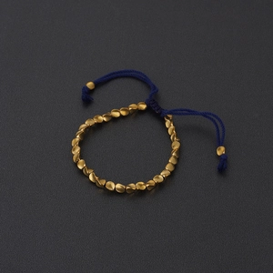 Detail of navy blue hand-woven cord bracelet with irregular gold-plated beads