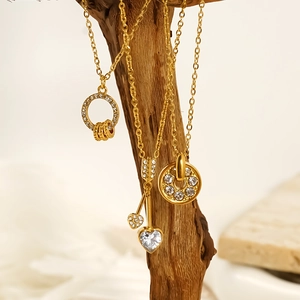 Gold stainless steel heart and arrow necklace with cubic zirconia pendants on wood branch