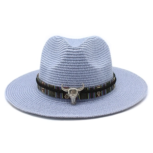Dettaglio di cappello in paglia azzurro con fascia etnica e ciondolo a testa di toro