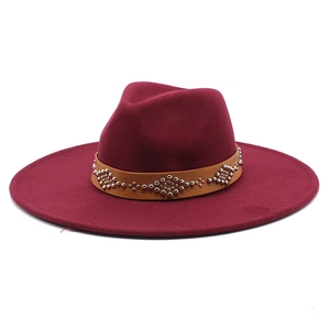 Dettaglio di cappello in lana bordeaux con fascia in pelle marrone e rivetti argento