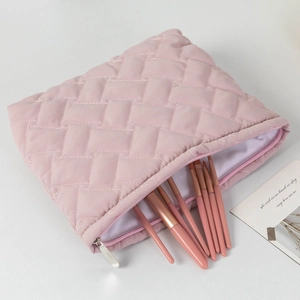 Pink quilted makeup bag detail showing soft diamond pattern and matching makeup brushes