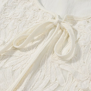 Detailed view of intricate white lace embroidery and delicate ribbon tie closure