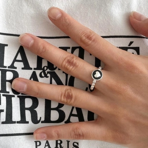 Detail of beaded silver ring with black enamel round inlay and white heart pattern