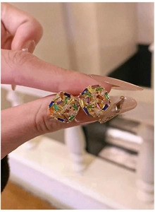 Macro shot of gold plated square stud earrings with vibrant colorful cubic zirconia stones