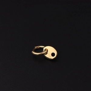 Detailed view of a gold coffee bean pendant earring with a polished finish on dark background