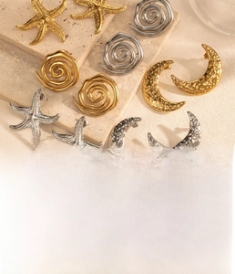 Macro detail of crescent moon and starfish stainless steel earrings in gold and steel finish