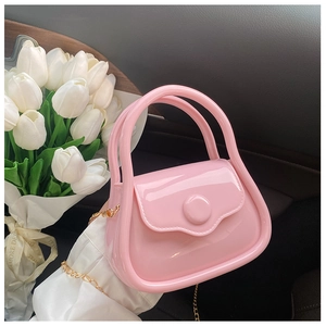 Close-up of pink mini jelly bag with gold chain strap held against tulip background
