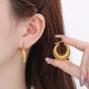 Close-up of golden croissant style hoop earrings with spiral texture for women
