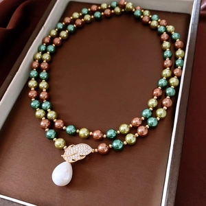 Detail of vintage double-layer pearl necklace with green beads and diamond leaf pendant