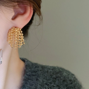 Detail view of gold-plated tassel earrings featuring multiple cascading beaded chains