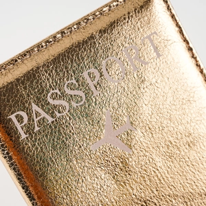 Macro detail of golden passport cover with textured synthetic leather and white aircraft icon