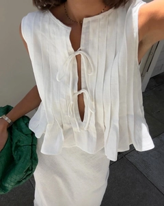 Detail of white linen pleated sleeveless top with bow ties and matching skirt set