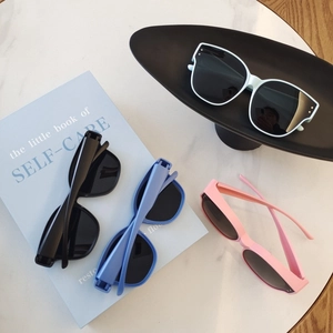 Detailed flat lay of oversized retro kids sunglasses in four colors on marble surface
