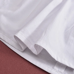 Macro detail of white pleated fabric showing fine stitching and smooth weave texture