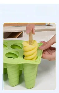 Détail du démoulage d'une glace spirale jaune d'un moule en silicone vert souple