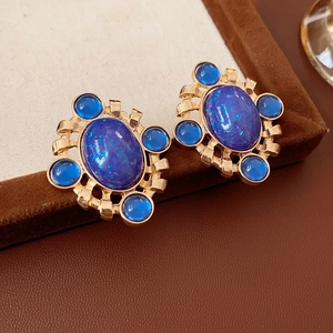 Macro shot of vintage gold earrings with deep blue oval stones and ornate retro details