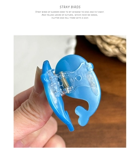 Detailed view of a cute blue dolphin hair claw clip with a glossy finish and metal spring